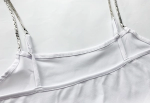 Detail of white bodycon dress featuring rhinestone metal chain straps and fine stitching