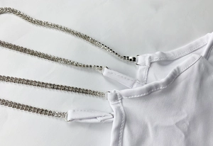 Detailed view of white dress featuring four slim straps with double-row rhinestone inlay