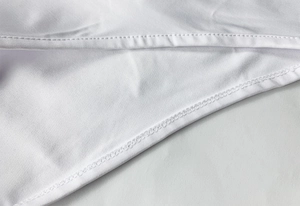 Macro shot of precise edge stitching and flatlock seams on white cotton bodysuit