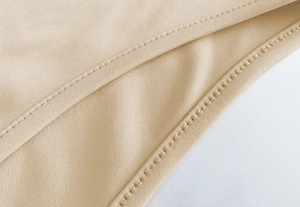 Macro view of stitching details on beige slim fit backless bodysuit for women