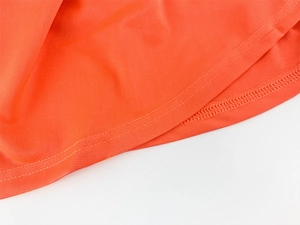 Vue détaillée montrant la double couture précise sur l'ourlet du tissu orange vif