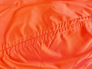 Vue détaillée du tissu orange froncé avec des coutures précises sur une jupe d'été moulante