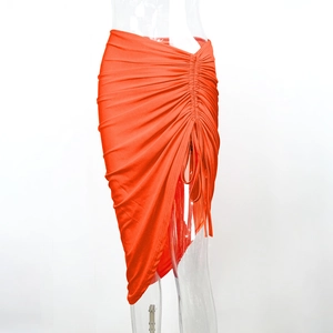Détail du cordon de serrage latéral et de l'ourlet irrégulier sur cette jupe moulante orange