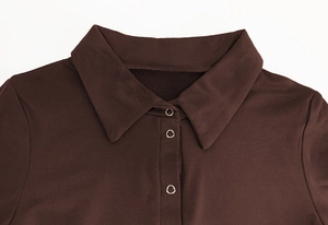 Macro detail of brown fleece bodysuit featuring pointed collar and silver metal snap buttons