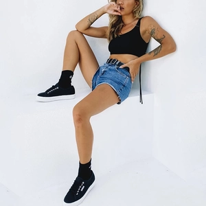 Close-up of black ribbed crop top with drawstring detail and frayed denim shorts