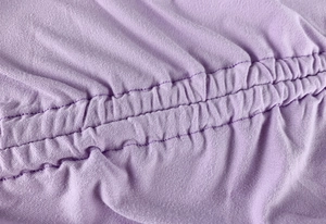 Detail of ruched lavender knit fabric showing professional double-needle stitching quality