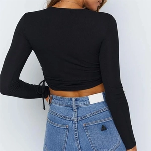 Detail of black ribbed cropped top with side drawstrings and blue denim jeans