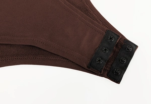 Detailed macro view of snap button closures on dark brown thermal fleece-lined bodysuit