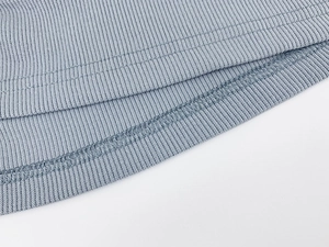 Close-up of light blue ribbed fabric showing detailed hem stitching and textile texture