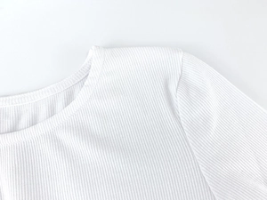 Detailed close-up of premium white ribbed knit fabric texture and shoulder stitching detail