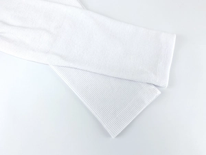 Detailed macro view of white ribbed knit fabric texture with fine machine-stitched hems