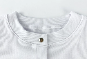 Detail of white ribbed knit bodysuit neckline with silver button and premium stitching