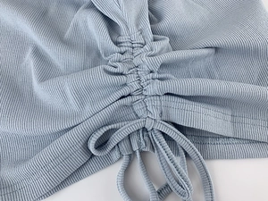 Detailed macro view of the light blue ribbed knit fabric with adjustable drawstring ruched hem