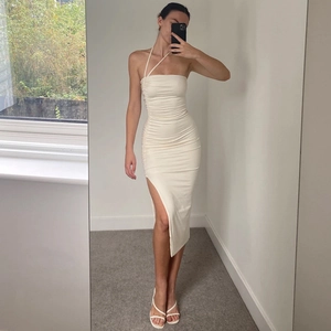 Detail of ruched waist and side slit on an elegant off-white bodycon halter dress
