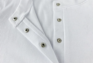 Macro shot of white ribbed bodysuit showing silver metal snap buttons and fabric texture