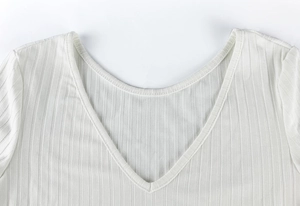 Gros plan détaillé sur la texture côtelée et l'encolure en V d'un body blanc en maille