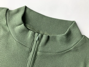 Détail de la robe en maille côtelée vert sauge avec col montant et fermeture éclair