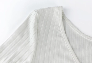 Gros plan sur la texture en maille côtelée blanche et le décolleté en V du body