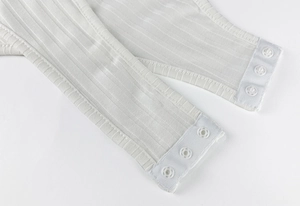 Détail de la fermeture à trois boutons-pression sur le body blanc en maille côtelée