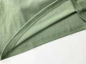 Détail de l'ourlet côtelé et des coutures sur une robe en maille vert clair