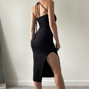 Detail of a black bodycon midi dress with backless halter neck and high side slit