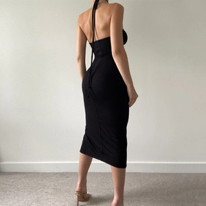 Close-up of ruched side slit and open back detail on a black bodycon midi dress