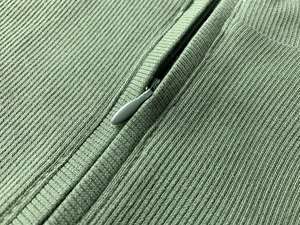 Détail d'une robe en maille côtelée vert sauge avec fermeture éclair invisible assortie
