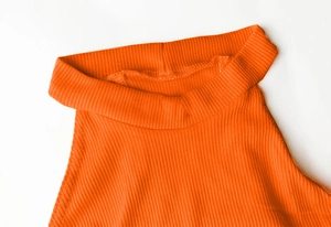 Vue détaillée du tissu en maille côtelée orange sur un body à col montant sans manches