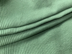 Vue macro du tissu en maille côtelée vert sauge avec détails de texture verticaux