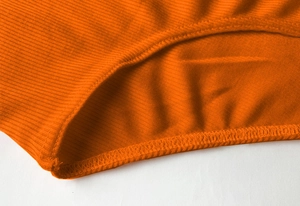 Détail macro du tricot côtelé orange vif avec des finitions de couture surjetées