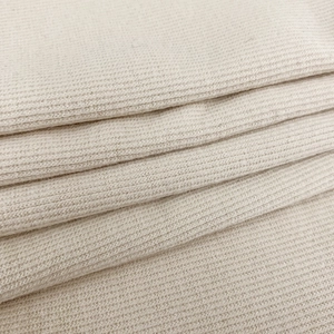 Gros plan sur la texture en maille côtelée beige d'un débardeur de sport court sans manches