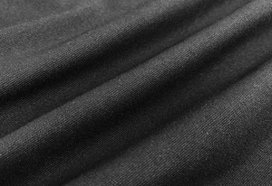 Vista macro del tessuto a maglia nero con trama a saia fine e morbide pieghe sulla veste