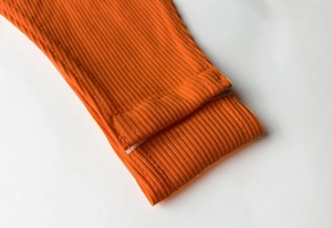 Détail macro du tissu en maille côtelée orange et coutures de qualité sur le body