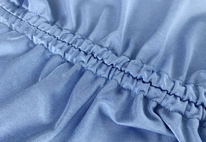 Macro shot of blue elastic ruched fabric detail with parallel stitching on dress
