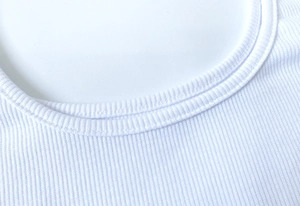Dettaglio del tessuto a costine bianco con cuciture precise sulla scollatura rotonda