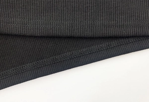 Détail de la double couture de qualité sur l'ourlet du haut en maille côtelée noire