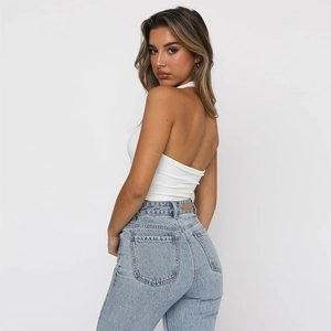 Chic white halter neck slim crop top paired with vintage wash high waist blue denim jeans