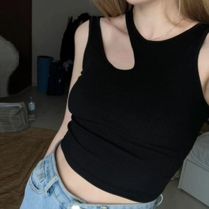 Vue détaillée du crop top sans manches noir côtelé avec découpe irrégulière au col