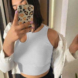 Détail du haut court en maille côtelée sous une veste en jean blanc montrant la coupe