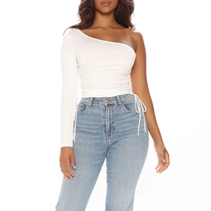 Detail view of adjustable side drawstrings and ruched texture on a white one-shoulder top