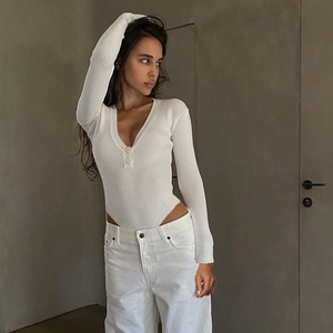 Close-up of white ribbed long-sleeve bodysuit featuring a deep V-neck with button detail