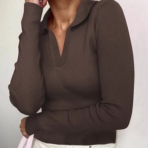 Detail eines dunkelbraunen gerippten Polo-Shirts mit tiefem V-Ausschnitt und enger Passform