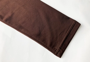Detailed view of flat double-needle stitching on dark brown knit dress sleeve cuff