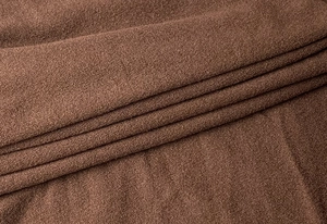 Macro shot of brown knit fabric showing soft fiber texture and elegant layered drapes