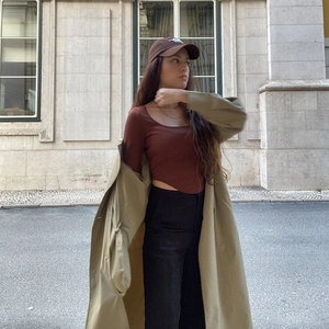 Close-up of brown long sleeve crop top styled with khaki trench coat and necklace
