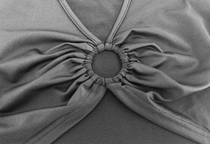Gros plan d'un haut noir avec anneau central et détails froncés sur le tissu élastique