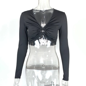 Détail d'un crop top noir à col en V avec anneau métallique central et plis froncés