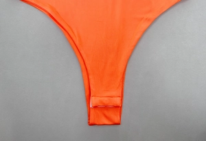 Close-up of snap closure at the crotch on a vibrant orange seamless bodysuit