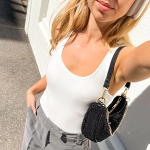 Chic black faux shearling crescent shoulder bag with leather strap and gold chain detail