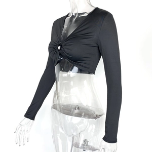 Détail d'un crop top noir à manches longues avec anneau métallique et col en V plissé